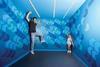 Man and woman in illusion room that makes man look giant and woman look tiny