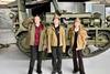 Three pupils stand in front of military vehicle while dressed in army clothing