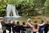 A group of students look at a waterfall