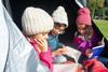Three children in a tent reading books during a school camping trip