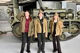 Three pupils stand in front of military vehicle while dressed in army clothing