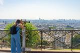 A teenage girl looks through a telescope at the sights in Paris