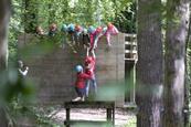 A group of students help a teenage girl up on the low level ropes course at a Conway Centre residential
