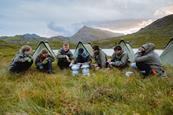 A group of teenagers in front of their tents in the Welsh countryside