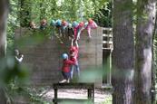 A group of students help a teenage girl up on the low level ropes course at a Conway Centre residential