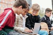 A group of children on a school trip looking at their laptop