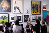A class in front of a wall of portraits during a guided session