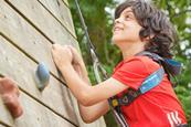 A boy climbs up a climbing frame at a PGL site