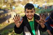 A boy with muddy hands taking part in an activity as part of the Waterways, Wildlife and Wellbeing project