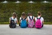 Girls with colorful Backpack Seated in front of Fountain