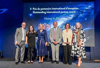 Staff from Visions in Education stand on stage at an awards event