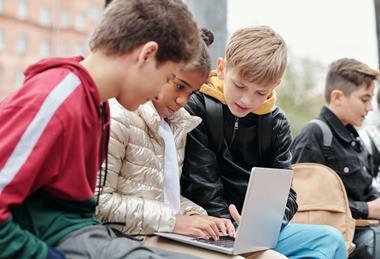 A group of children on a school trip looking at their laptop