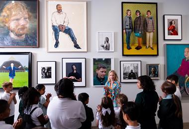 A class in front of a wall of portraits during a guided session
