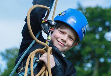A boy swinging on a rope at a Conway Centres school trip