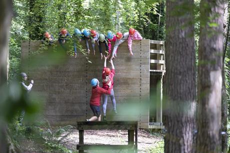 A group of students help a teenage girl up on the low level ropes course at a Conway Centre residential