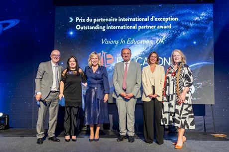 Staff from Visions in Education stand on stage at an awards event
