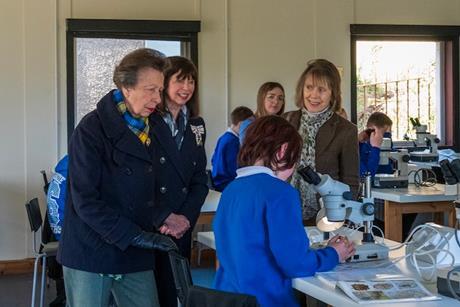 Princess Anne watches young boy working in a science laboratory