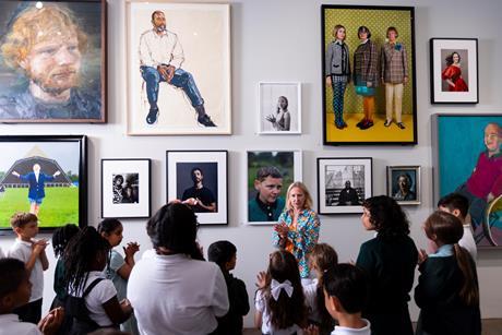 A class in front of a wall of portraits during a guided session