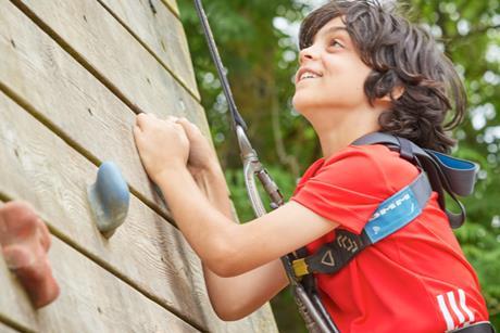A boy climbs up a climbing frame at a PGL site