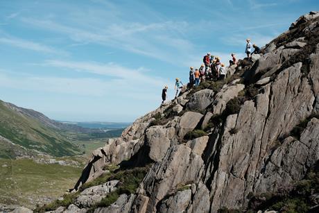 A group of young people undertake an outdoor residential adventure on top of rocks with The Outward Bound Trust. 
