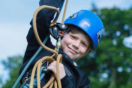 A boy swinging on a rope at a Conway Centres school trip