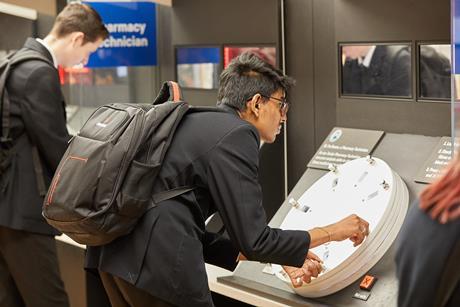 A student leans over an interactive museum exhibit