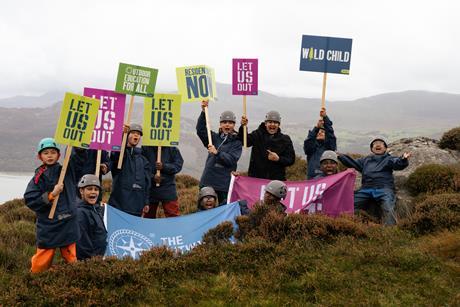 A group of young people hold banners and flags supporting the Let Us Out campaign to make outdoor residentials part of the school curriculum