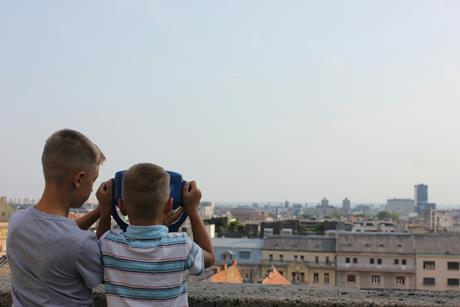 Two boys looking through a viewing projector in a city.