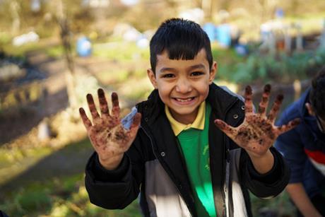 A boy with muddy hands taking part in an activity as part of the Waterways, Wildlife and Wellbeing project