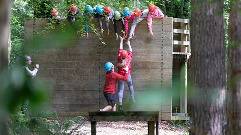A group of students help a teenage girl up on the low level ropes course at a Conway Centre residential