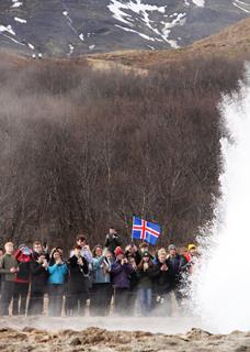 A group of students stand in awe watching Iceland's Great Geysir erupt.
