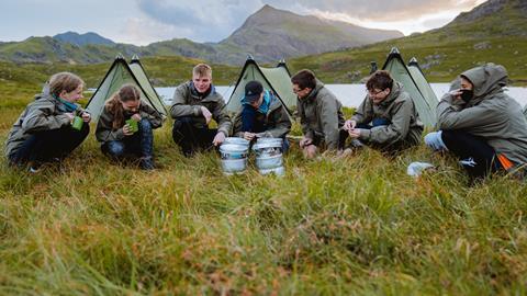 A group of teenagers in front of their tents in the Welsh countryside