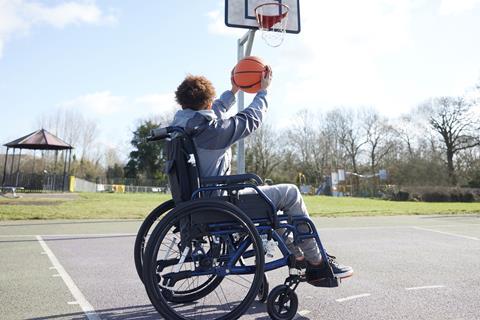 School pupil in a wheelchair shooting a basketball towards a hoop