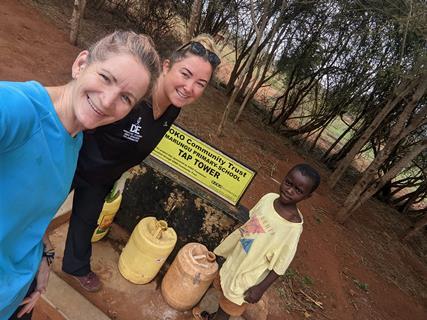 Two women wih a Kenyan child and a water project