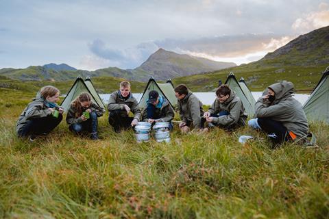 A group of teenagers in front of their tents in the Welsh countryside