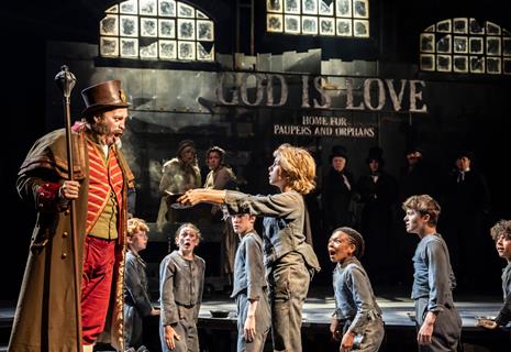 Oliver asks Mr Bumble for more gruel in the 2025 West End production of Oliver!