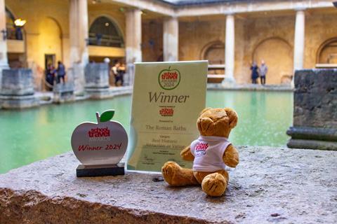 STO mascot, Teacher Ted and a School Travel Awards trophy sat at the historic Roman Baths in Bath which was a winner in 2024.