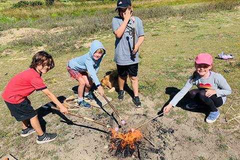 Children toast marshmallows on a fire with Wild Adventures in Jersey