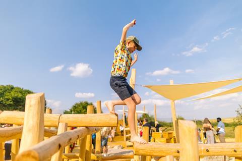 A boy walks across a wooden play area