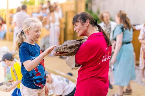 A young girl strokes a toy reptile