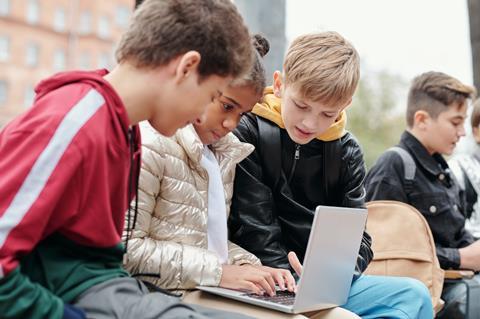 A group of children on a school trip looking at their laptop