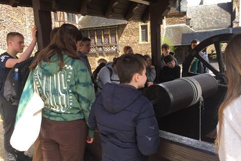 A group of students huddle around an old wooden well