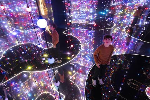 Young boy surrounded by hanging coloured lights in immersive exhibit