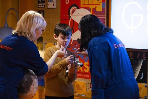 Two museum staff show young boy a space-related toy
