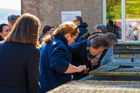 Princess Anne and charity staff peer into an outdoor container