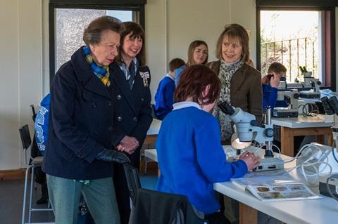 Princess Anne watches young boy working in a science laboratory