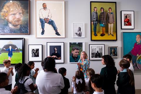A class in front of a wall of portraits during a guided session