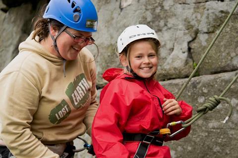 A young girl climbing a wall with a Lost Earth Adventures instructor