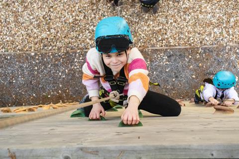 A girl climbs a wall at Avon Tyrrell Outdoor Centre