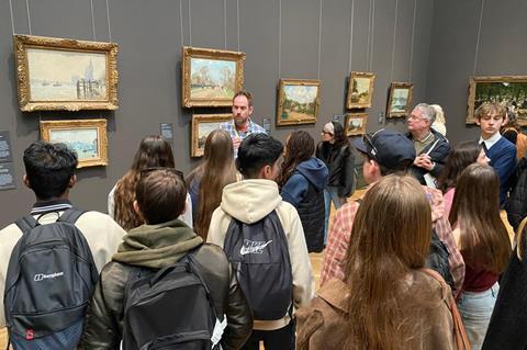 A group of students standing in front of paintings in a gallery
